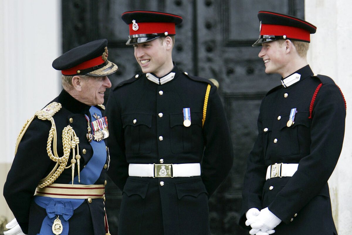 Dalam file foto 12 April 2006 ini, Pangeran Philip (kiri), berbicara dengan cucunya, Pangeran William (tengah) dan Pangeran Harry (kanan), setelah The Sovereign's Parade di Royal Military Academy di Sandhurst, Inggris. 