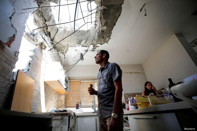 Adi Vaizel looks at damage to his house after it was hit by a rocket launched from the Gaza Strip this week, in Ashkelon, Israel, May 20, 2021. News reports said Israel's security cabinet and Hamas on Thursday had approved a tentative cease-fire.