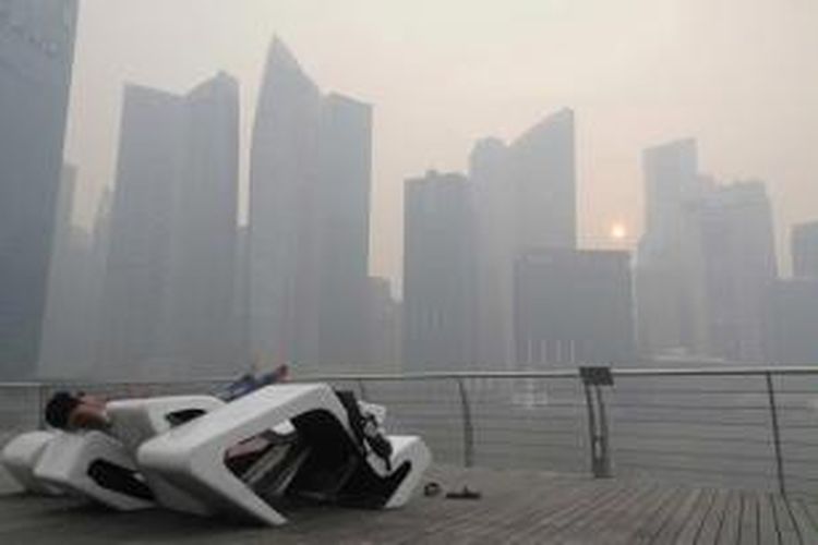 Seorang pria beristirahat di Singapore Central Business District yang tengah diselimuti kabut asap, 20 Juni 2013.  Kabut asap berasal dari kebakaran hutan di Sumatera, Indonesia.