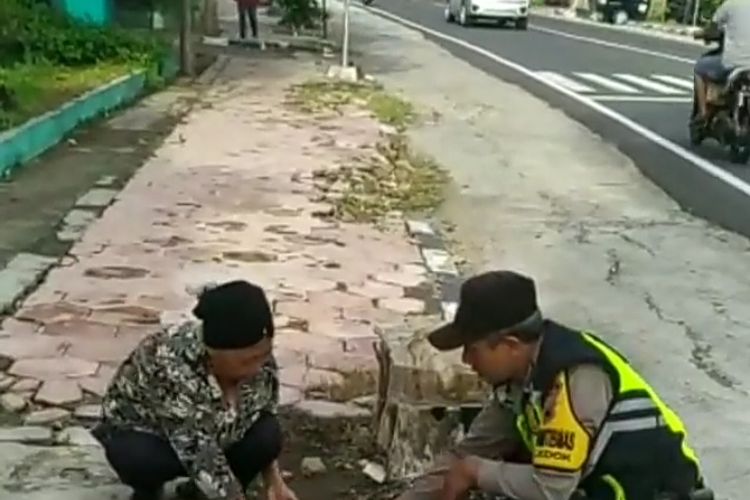 Aipda Adi Novianto membantu seorang ibu memungut beras yang jatuh.