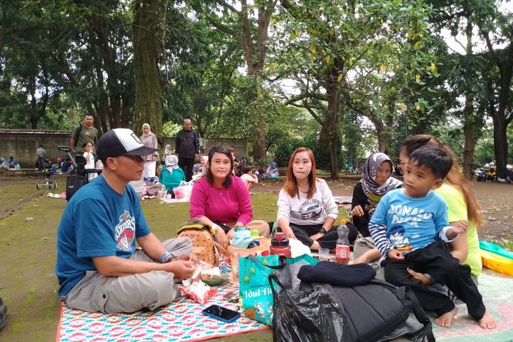 Keluarga Awan Rusmawan saat botram atau makan bersama usai lelah berkeliling di Kebun Binatang Bandung, Kota Bandung, Jawa Barat, Kamis (11/4/2024).