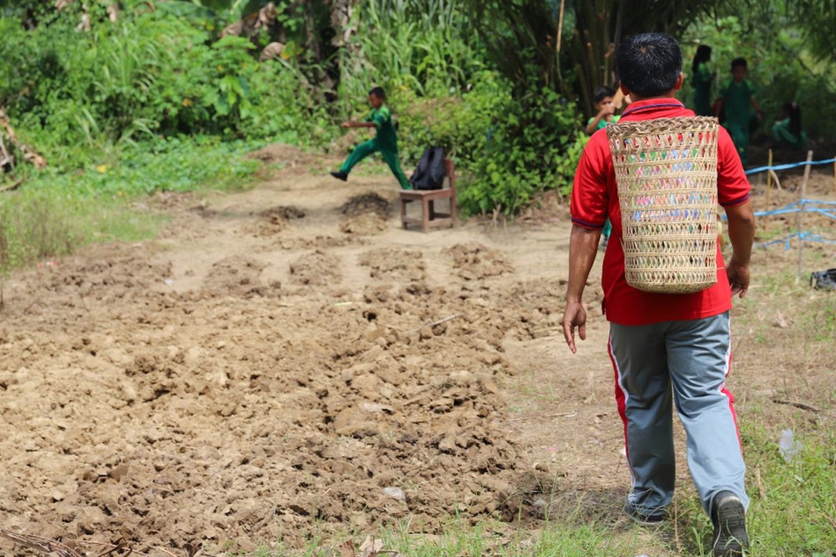 Yosep berjalan menuju ladang sambil memanggul buku dengan menggunakan ajat. Yosep merawat nasionalisme di pedalaman Kaltara dengan mendekatkan buku kepada anak.