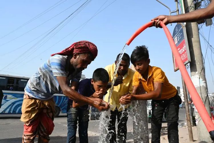 Orang-orang sedang minum air dan mencuci muka dari pipa air pinggir jalan saat gelombang panas terjadi di Dhaka, Bangladesh, pada 23 April 2024.