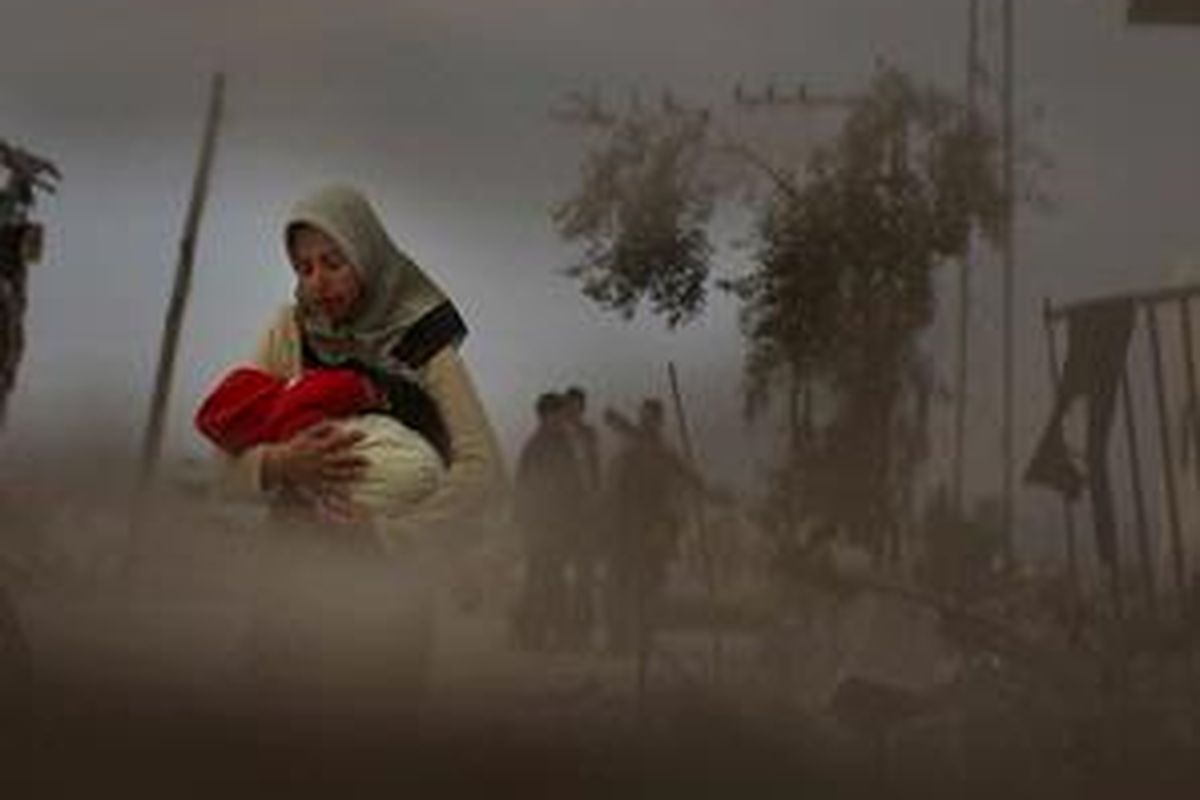 Seorang wanita menggendong bayinya di kawasan perumahan yang hancur di pinggiran Kota Gaza, 23 Januari 2009. Penduduk Gaza masih kekurangan pangan dan air bersih akibat serangan Israel.