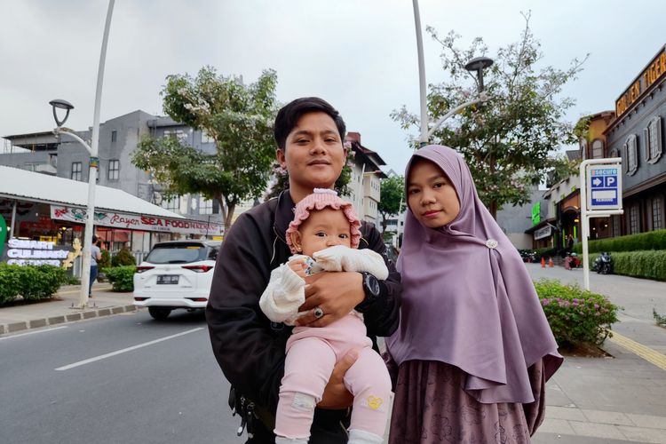 Melisa (24) dan Maulana (28) sedang mengajak buah hatinya jalan-jalan sore menikmati panorama bunga Tabebuya yang sedang mekar di Jalan Kemang Raya, Jakarta Selatan pada Minggu (17/9/2023) sore.