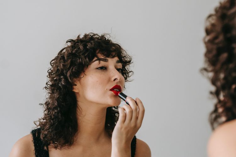 Ilustrasi seorang wanita menggunakan lipstik.