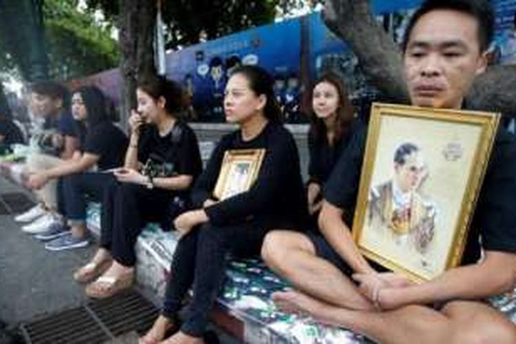 Jutaan warga Thailand di Bangkok, ibu kota negara itu, telah berada di sepanjang tepi jalan yang akan dilalui saat perarakan peti jenazah Raja Bhumibol dari rumah sakit menuju Grand Place, di pusat kota, Jumat (14/10/2016). Mereka mengenakan pakaian hitam sambil memegang foto raja.