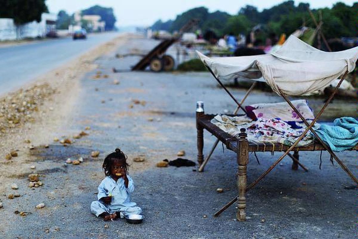 Seorang bocah perempuan Pakistan duduk di tepi jalan sambil memakan jeruk saat bersama keluarganya mengungsi di tepi jalan menuju Tando Allah Yar, Senin (26/9). Keluarga bocah itu terpaksa mengungsi karena kampung mereka dilanda banjir.