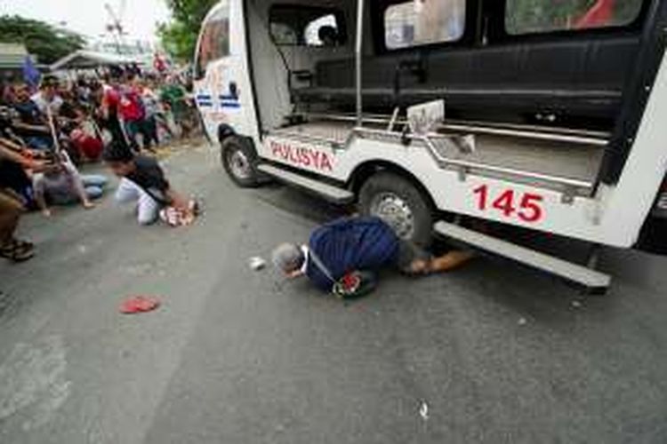 Seorang pria terjebak di bawah sebuah mobil patroli polisi yang menabrak pengunjuk rasa yang berkumpul di depan kantor kedubes AS di Manila.