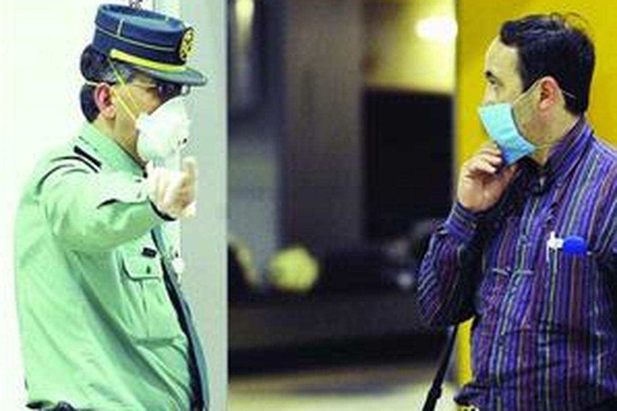 Seorang polisi Spanyol (kiri), mengenakan masker, memberikan instruksi kepada penumpang pesawat terbang yang baru tiba dari Meksiko di bandar udara Madrid, Senin (27/4). Pemerintah Spanyol mengonfirmasikan bahwa ada seorang warganya yang baru kembali dari Meksiko terjangkit flu babi.