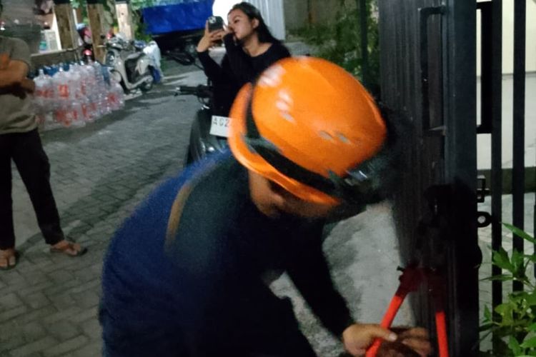 Petugas Dinas Pemadam Kebakaran dan Penyelamatan Kabupaten Nganjuk saat mencoba membuka gerbang rumah Vira yang terkunci, Selasa (29/7/2025) pagi
