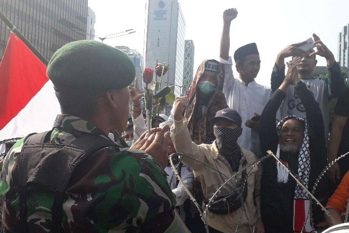 Seorang prajurit TNI menerima bunga mawar dari massa peserta aksi unjuk rasa di depan Kantor Bawaslu RI di Jalan MH Thamrin, Jakarta Pusat, Rabu (22/5/2019).