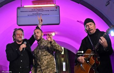 Dua personel band U2, yakni vokalis  Paul David Hewson atau Bono (kiri) dan gitaris David Howell Evans atau The Edge (kanan), tampil bersama penyanyi militer Ukraina Taras Topolia (tengah) di stasiun bawah tanah yang kini menjadi tempat perlindungan di Kyiv, Ukraina, Minggu (8/5/2022).