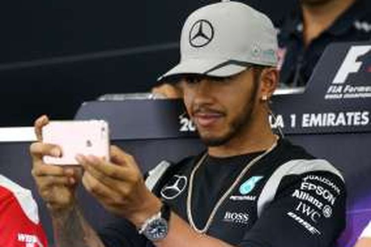 Pebalap Mercedes AMG Petronas F1 asal Inggris, Lewis Hamilton, memegang telepon selulernya saat konferensi pers jelang digelarnya GP Jepang di Sirkuit Suzuka, Kamis (6/10/2016).