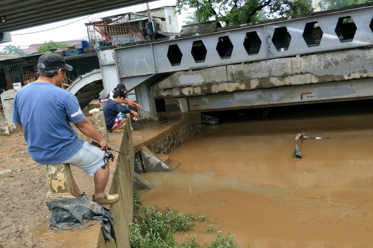 Warga Kelurahan Rawajati, Jakarta Selatan, memancing ikan di Sungai Ciliwung, Selasa (6/2/2018). Mereka memancing setelah air sungai, yang sempat meluap dan menyebabkan banjir di permukiman warga, telah surut.