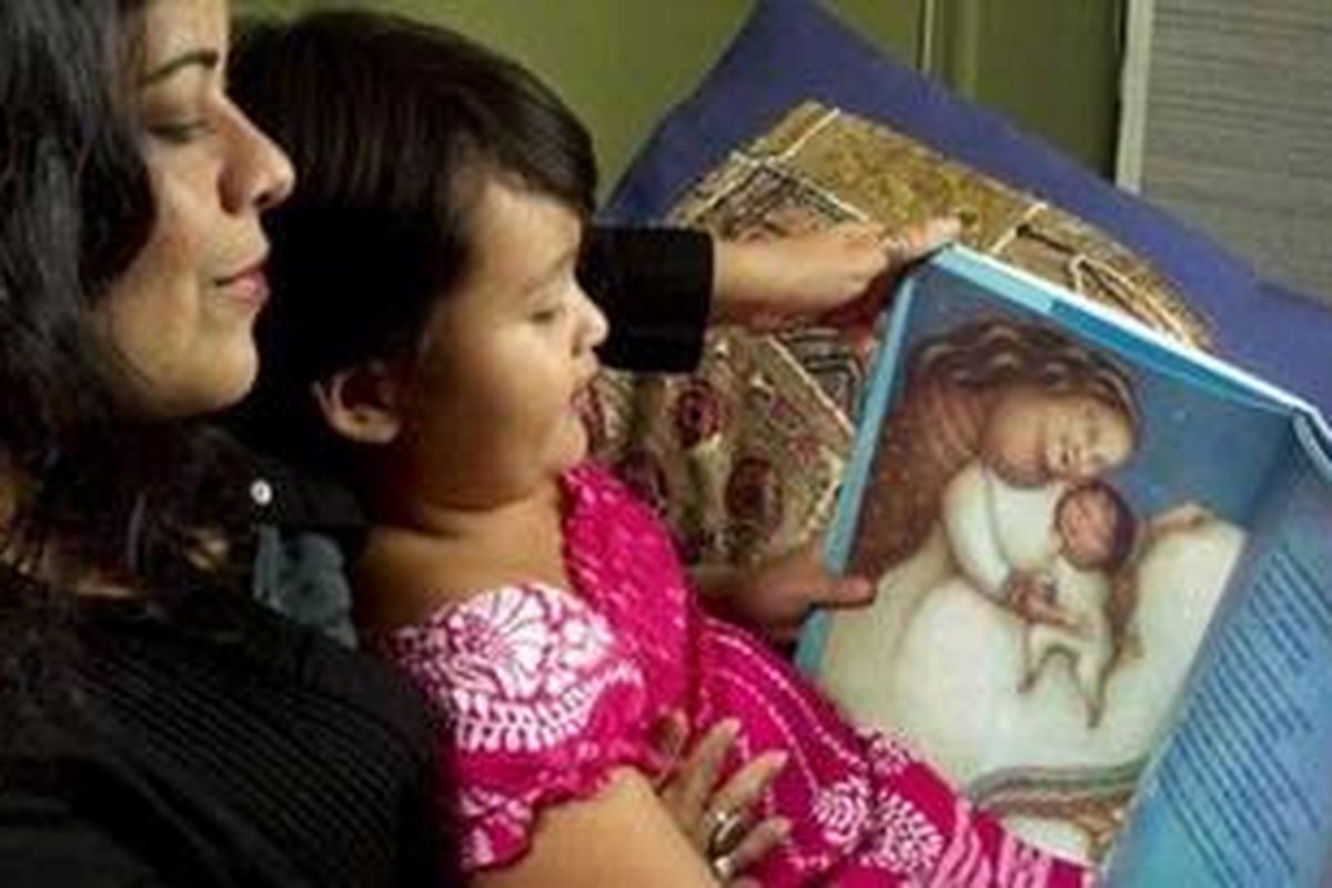 This Tuesday, March 29, 2011 photo shows Maya Soetoro-Ng, left, and her daughter Suhaila Ng, 6, as they look at Soetoro-Ngs new book, "Ladder to the Moon," at their home in Honolulu. Soetoro-Ng, President Obamas sister, draws on memories of their mother, Ann Dunham, for her new picture book.