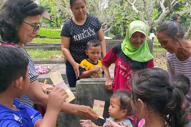 Keturunan Tionghoa yang berziarah kepada leluhur di Bong Cina Giripeni, Kapanewon Wates, Kulon Progo, Daerah Istimewa Yogyakarta, membagi-bagikan angpao kepada anak-anak dan ibu-ibu yang sejak pagi berkumpul di pemakaman itu, Selasa (1/2/2022).