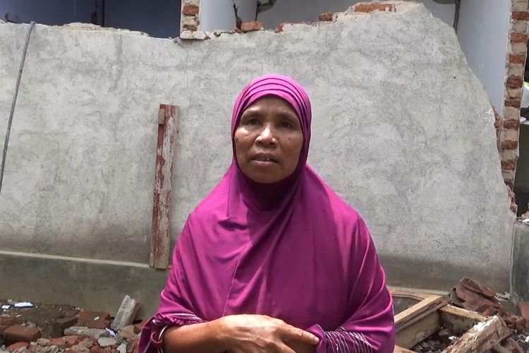 Ibu Rumida di belakang rumahnya yang terdampak gempa, Kamis (21/3/2019).