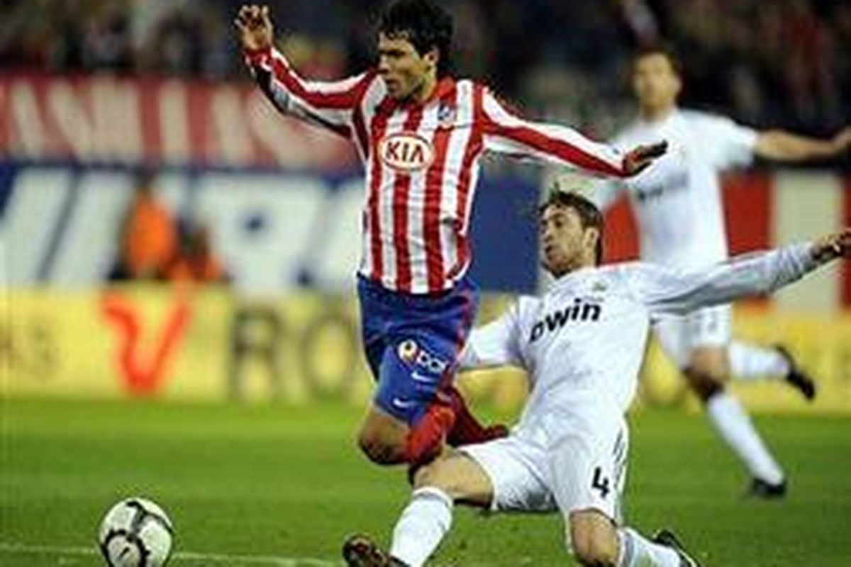 Defender Real Madrid, Sergio Ramos (kanan) terpaksa menekel Sergio Aguero demi menyelamatkan pertahanannya. Ramos akhirnya harus keluar karena terkena dua kartu kuning.