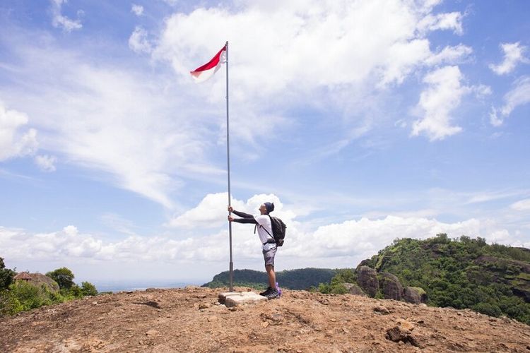 Ilustrasi memasang bendera Indonesia di puncak gunung. 