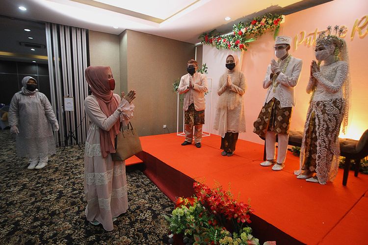 Tamu undangan memberikan ucapan selamat kepada pasangan pengantin Kumala dan Putri beserta keluarganya dengan menjaga jarak fisik saat simulasi resepsi pernikahan di masa normal baru di Hotel Royal Singosari Cendana, Surabaya, Jawa Timur, Senin (6/7/2020). Kegiatan simulasi resepsi pernikahan tersebut bertujuan untuk mengedukasi masyarakat tentang pentingnya penerapan protokol kesehatan dalam acara pernikahan guna mencegah penyebaran dan penularan COVID-19 di masa normal baru.