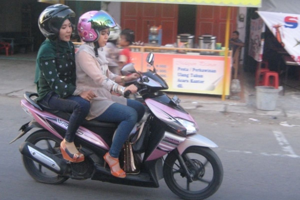 Dua perempuan yang mengenakan celana jins ketat dan duduk mengangkang mengendarai sepeda motor di Kota Lhokseumawe, Provinsi Aceh, Minggu (23/6/2013), meskipun ada larangan mengenakan celana jins ketat dan duduk mengangkang bagi kaum perempuan yang dibonceng sepeda motor.