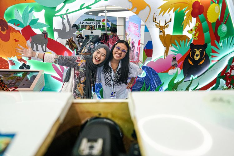 Pengunjung sedang mencoba pengalaman seru berfoto di Sustainability Photowall milik booth Pertamina yang tersedia di GIIAS 2025.