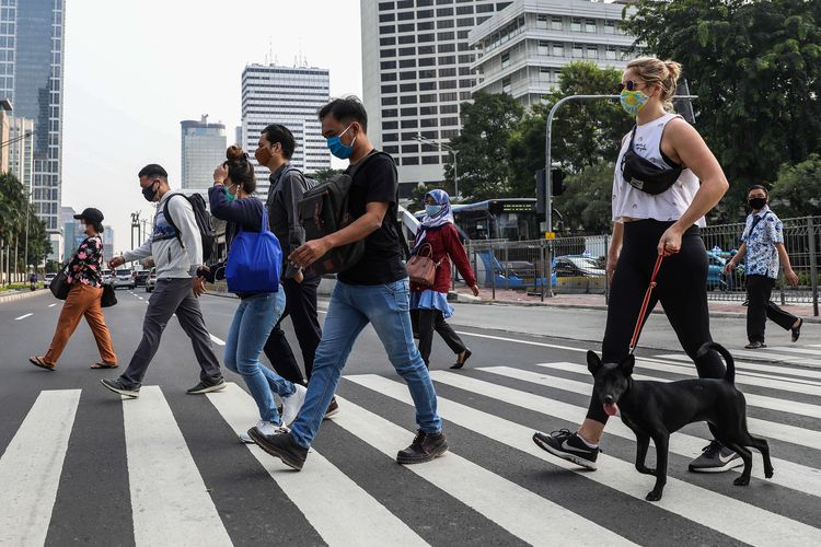 Pekerja yang menggunakan masker saat menyebrangi zebra cross di Jalan M.H Thamrin, Jakarta Pusat, Senin (14/9/2020). PSBB kembali diterapkan tanggal 14 September 2020, berbagai aktivitas kembali dibatasi yakni aktivitas perkantoran, usaha, transportasi, hingga fasilitas umum.