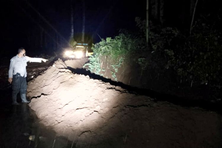 Seorang polisi menunjuk material tanah yang longsor dari tebing di Desa Ampelgading, Kecamatan Selorejo, Kabupaten Blitar, Kamis (18/11/2021) malam