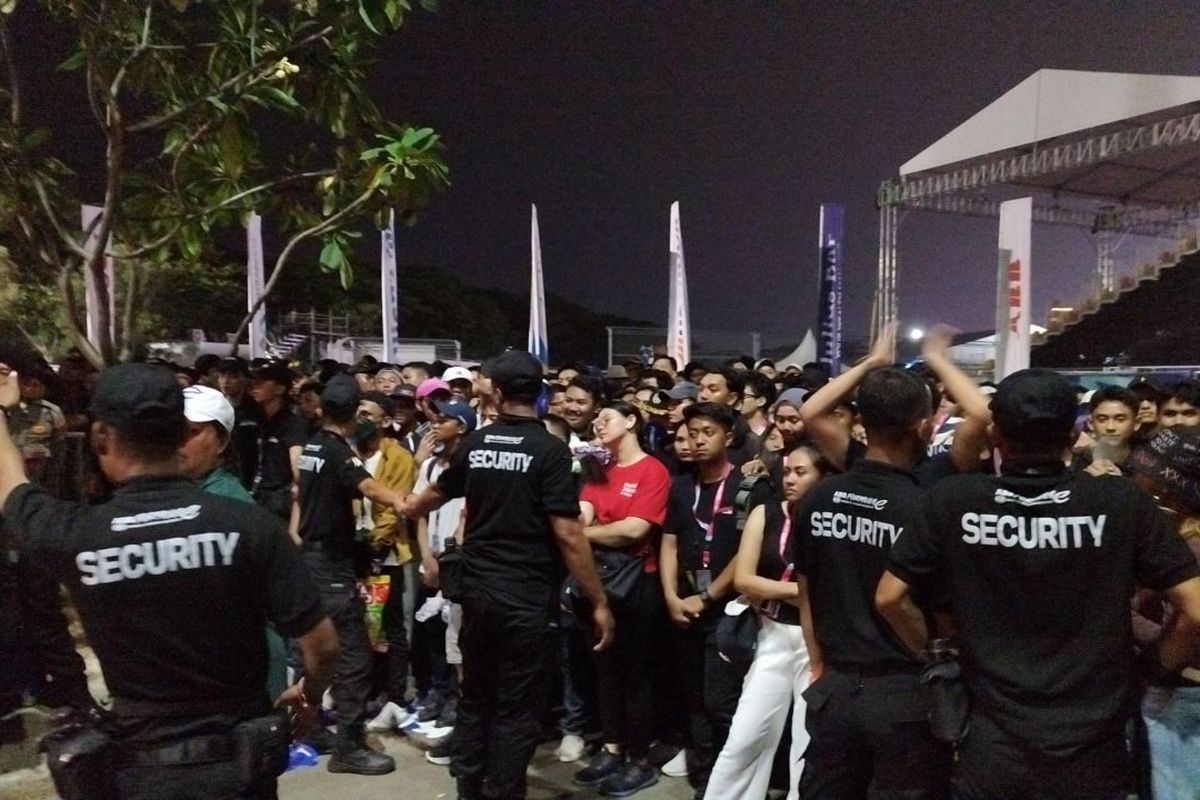 Petugas keamanan saling membentuk barikade untuk mencegah penonton menerobos antrean demi masuk shuttle bus usai Formula E 2023 di Pintu Bende, Ancol, Jakarta Utara, Minggu (4/6/2023). (KOMPAS.com/XENA OLIVIA)