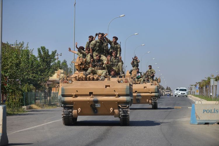 Anggota dari Pasukan Nasional Suriah, kelompok pemberontak yang didukung Turki, melambai ketika mereka melintas kota perbatasan Ceylanpinar di Provinsi Sanliurfa menuju Suriah pada 10 Oktober 2019.