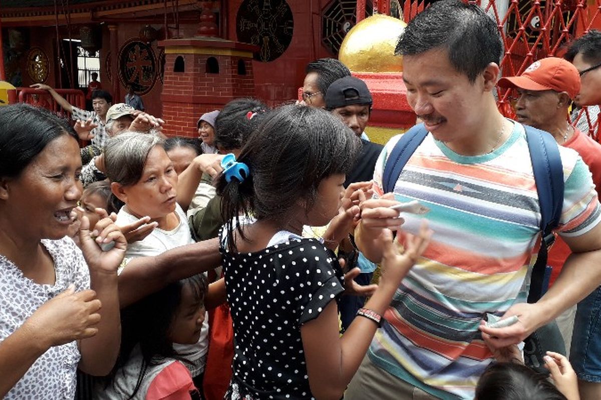 Seorang pria membagikan uang pecahan Rp 2000 kepada keluarga anak jalanan yang berkumpul di pintu masuk Wihara Dharma Bhakti, Glodok, Jakarta Barat pada Senin (12/2/2018).