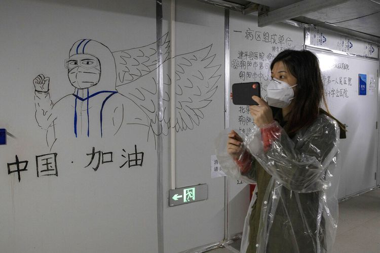 Seorang pengunjung melihat karya seni dengan tulisan Go China yang ditinggalkan oleh pekerja di Rumah Sakit Leishenshan yang dibangun di tempat parkir dari modul prefabrikasi dalam dua minggu di Wuhan di provinsi Hubei, China tengah, Sabtu, 11 April 2020.