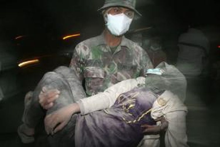 Seorang anggota TNI membopong pengungsi yang pingsan tak lama setelah Gunung Kelud meletus Kamis (13/2/2014) malam.