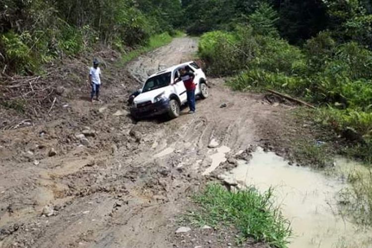 Dua buah mobil mencoba menerobos ruas jalan yang mengalami kerusakan parah di  sebuah hutan di  Kabupaten Seram Bagian Timur, Maluku, Minggu (27/1/2019)