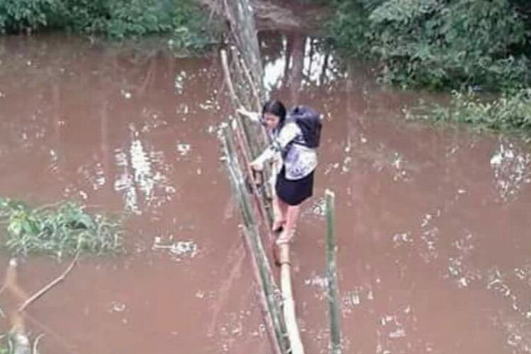 Foto Lusia ketika menyeberangi sungai saat hendak berangkat mengajar yang diunggah akun facebook Askiman Sintang (18/3/2017)