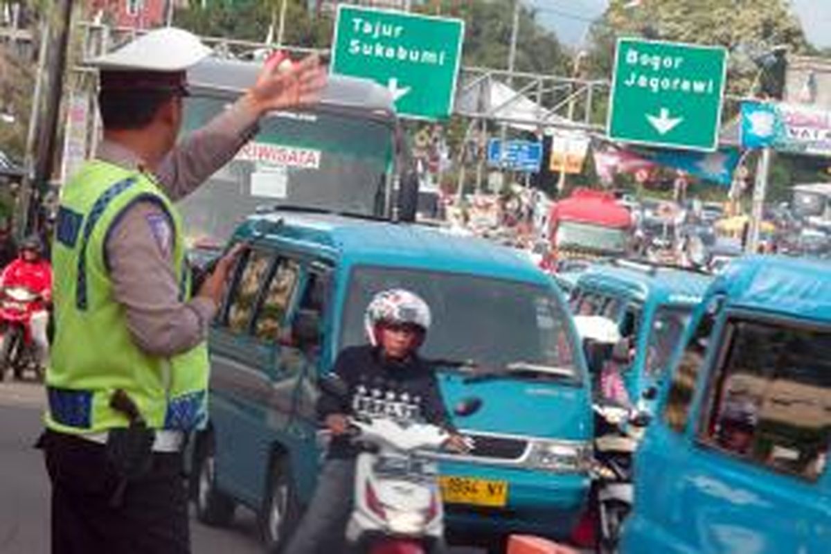 Petugas Lalu Lintas Polres Bogor mengatur kendaraan yang melintas ke arah Puncak, Minggu (27/12/2015).