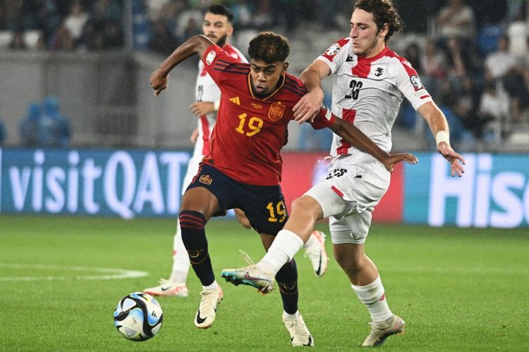 Pemain muda timnas Spanyol, Lamine Yamal (kiri), berusaha melewati adangan gelandang Georgia, Luka Gagnidze, dalam matchday kelima Grup A Kualifikasi Euro 2024 yang digelar di Stadion Boris Paichadze Dinamo Arena, Tbilisi, pada Jumat (8/9/2023) malam WIB. Pada penampilan perdananya bersama timnas Spanyol, Lamine Yamal langsung memecahkan dua rekor sekaligus. (Foto oleh VANO SHLAMOV/AFP)