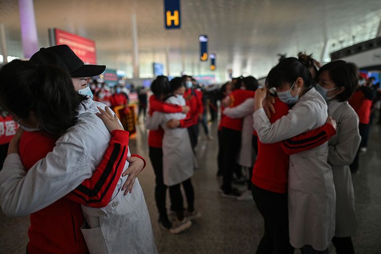 Para petugas medis dari Provinsi Jilin menangis memeluk rekan yang bersama-sama selama menangani pasien corona, dalam sebuah acara perpisahan di Bandara Tianhe yang baru dibuka kembali di Wuhan, Hubei, China, Rabu (8/4/2020). Ribuan orang bergegas meninggalkan Wuhan setelah otoritas mencabut kebijakan lockdown selama lebih dari dua bulan di lokasi yang diketahui sebagai episenter awal virus corona tersebut.