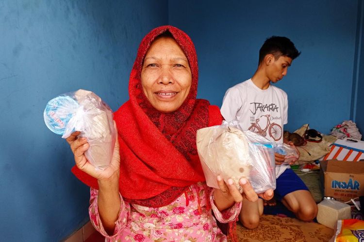 Salah satu pengungsi di Terminal Pal 6 Banjarmasin, memperlihatkan nasi bungkus yang didapatkannya dari para relawan, Senin (18/1/2020). 