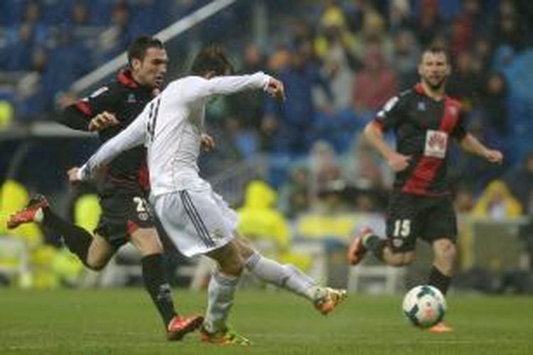 Pemain sayap Real Madrid Gareth Bale melepaskan tembakan yang berujung gol pertamanya (dari dua) ke gawang Rayo Vallecano, pada pertandingan Primera Division La Liga, di Santiago Bernabeu, Sabtu (29/3/2014). Madrid memenangi laga itu dengan skor 5-0. 