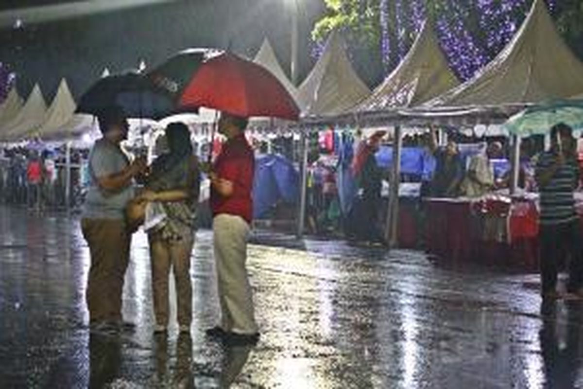 Pengunjung Kaki Lima Night Market di Jalan Medan Merdeka Selatan tetap berbelanja walaupun hujan deras mengguyur, Sabtu (12/10/2031) malam. 