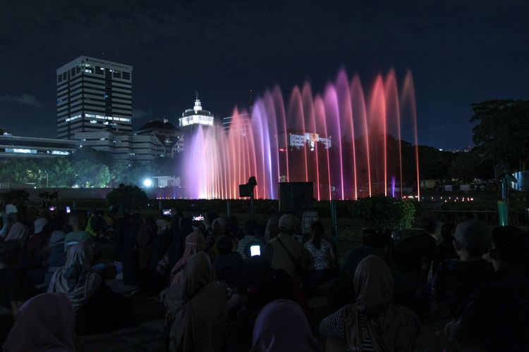 Atraksi air mancur menari di Monumen Nasional, Jakarta, Selasa (25/4/2023) malam. Selain air mancur menari, pengunjung juga bisa menyaksikan pertunjukan video mapping di dinding tugu Monumen Nasional untuk mengisi libur Learan 2023.