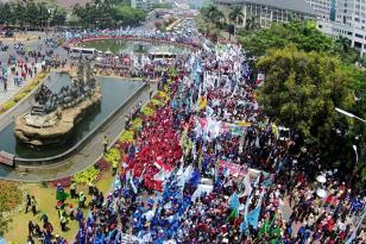 Buruh melakukan aksi unjuk rasa di Bundaran Patung Kuda, Jl MH Thamrin, Jakarta, Selasa (1/9/2015). Dalam aksi ini mereka menuntut pemerintah menurunkan harga sembako, menolak PHK akibat perlambatan ekonomi, hingga kenaikan upah pada 2016.