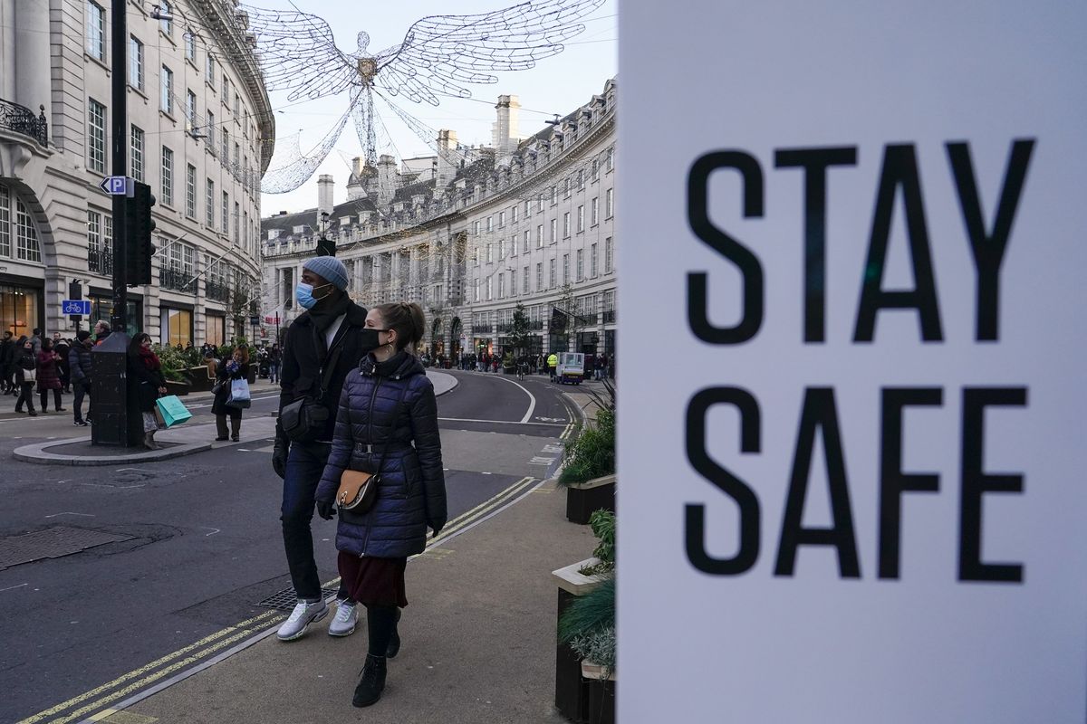 Orang-orang mengenakan masker saat berjalan di Regent Street, London, Minggu (28/11/2021). Perdana Menteri Inggris Boris Johnson mengumumkan pengetatan prokes dan pembatasan, setelah ditemukan tiga kasus Covid-19 varian Omicron di negara itu. Warga wajib memakai masker lagi di toko-toko dan transportasi umum.