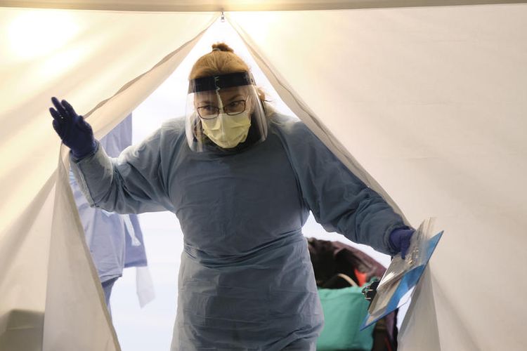 Seorang perawat memasuki tenda perawatan dengan membawa alat uji virus corona, di stasiun drive-thru University of Washington Medical Center, Seattle, Washington, Amerika Serikat, 16 Maret 2020.