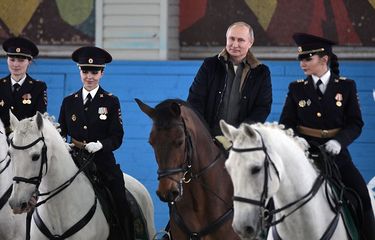 Presiden Rusia Vladimir Putin menunggangi kuda bersama petugas polisi wanita saat peringatan Hari Perempuan Internasional di Moskwa, Kamis (7/3/2019).