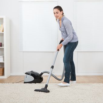 Ilustrasi membersihkan karpet dengan vacuum cleaner. 