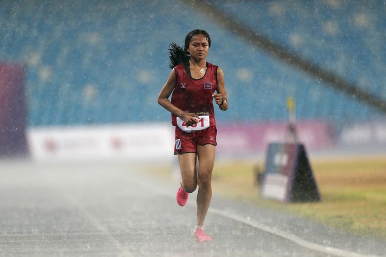 Pelari Kamboja, Bou Samnang, saat mengikuti lomba final lari 5000 meter putri SEA Games 2023 yang digelar di Olympic Stadium, Phnom Penh, pada Senin (8/5/2023). Bou Samnang tetap melanjutkan lomba sampai finis meski lintasan diguyur hujan lebat. (Foto oleh DUC DONG/AFP)