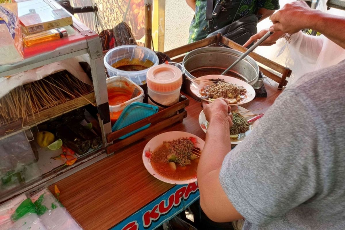 Ilustrasi: Penjual menuangkan kupang dan kuah ke piring.